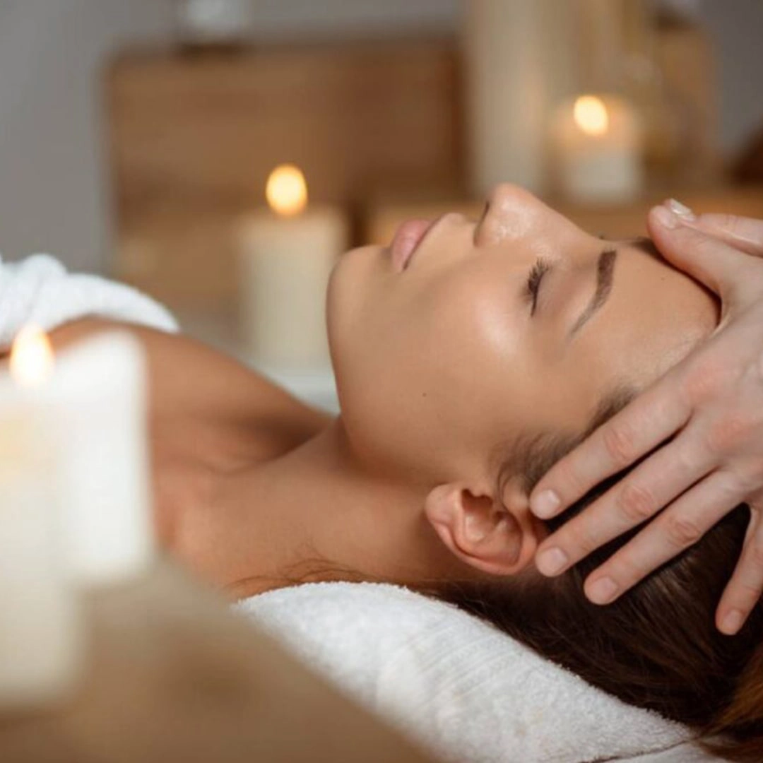 Rituel détente avec massage du visage dans une ambiance aux bougies, illustrant l’Offre Évasion des Sens : 2 nuitées à l’Hôtel Antares & Spa Honfleur.