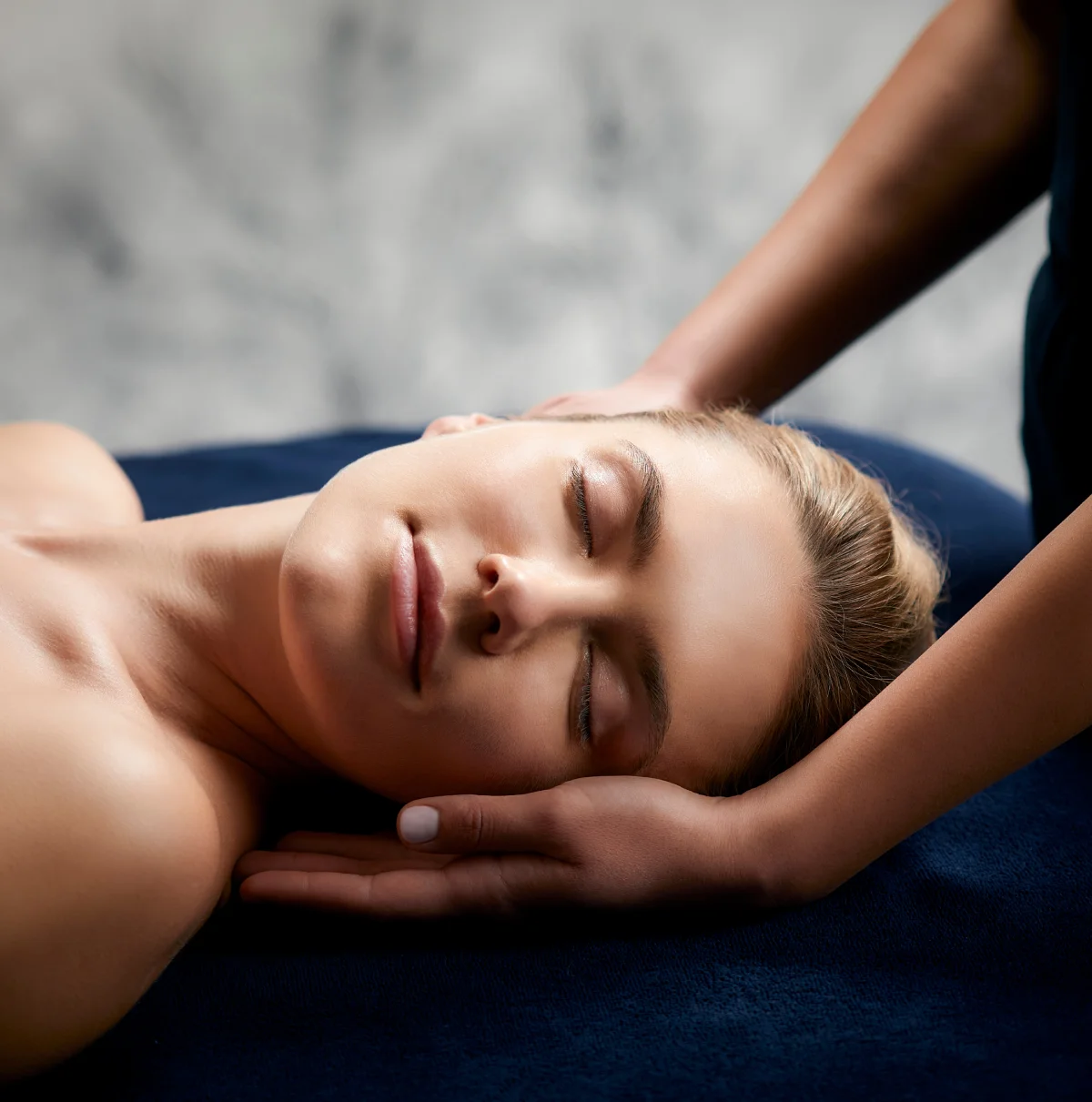 Soin PHYTOMER au spa avec une cliente allongée, les mains du praticien soutenant sa tête, à l’Hôtel Antares & Spa Honfleur.