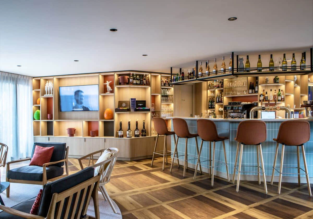 Bar et espace salon de l’Hôtel Antares à Honfleur avec comptoir et fauteuils