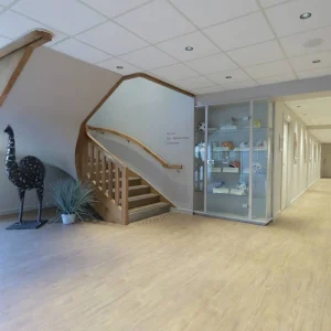 Hall d'accueil lumineux avec escalier en bois et sculpture de l'Hôtel Antarès Honfleur