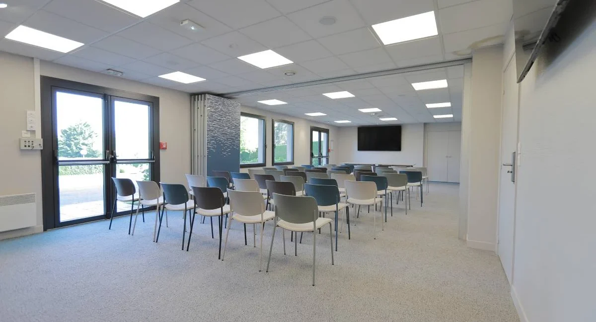 Salle de réunion modulable de l’Hôtel Antares à Honfleur avec disposition conférence et écran de présentation